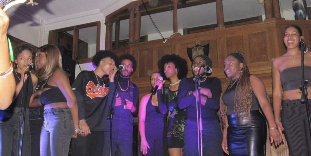A group of black students sing on stage at a performance